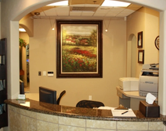 Modern dental office reception area with desk, framed landscape artwork, and welcoming cream-colored walls.