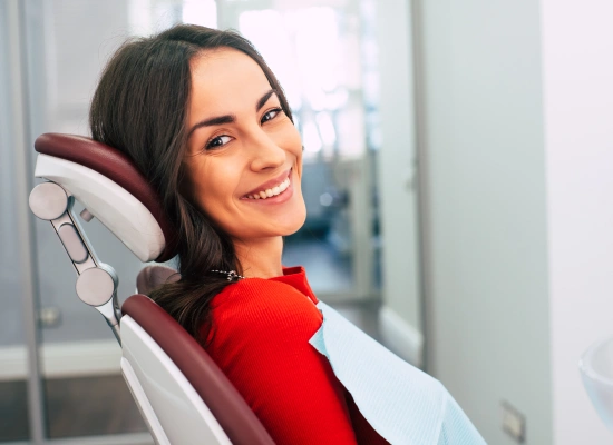 Woman in red shirt smiling in dental chair at modern dental office