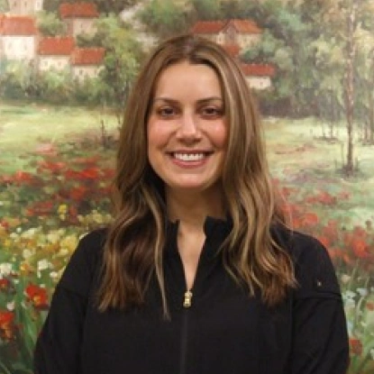 Woman smiling at camera wearing black shirt against floral garden painting backdrop.