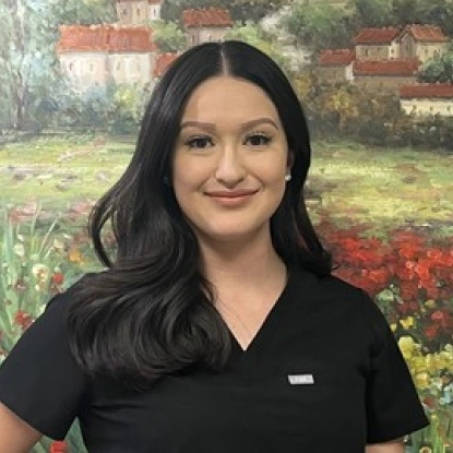 Professional woman in black scrubs smiling at dental office, garden backdrop