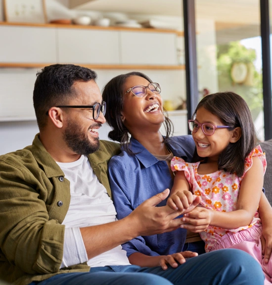 Happy family of three smiling together in modern dental office waiting room.