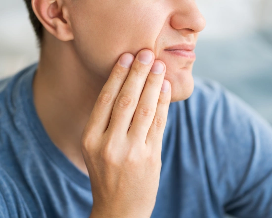 Man touching jaw in discomfort, suggesting dental pain or tooth sensitivity concerns.